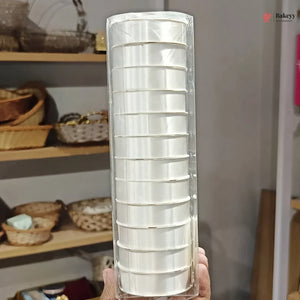 Packaged set of white disposable cups held in front of a shelf with baskets.