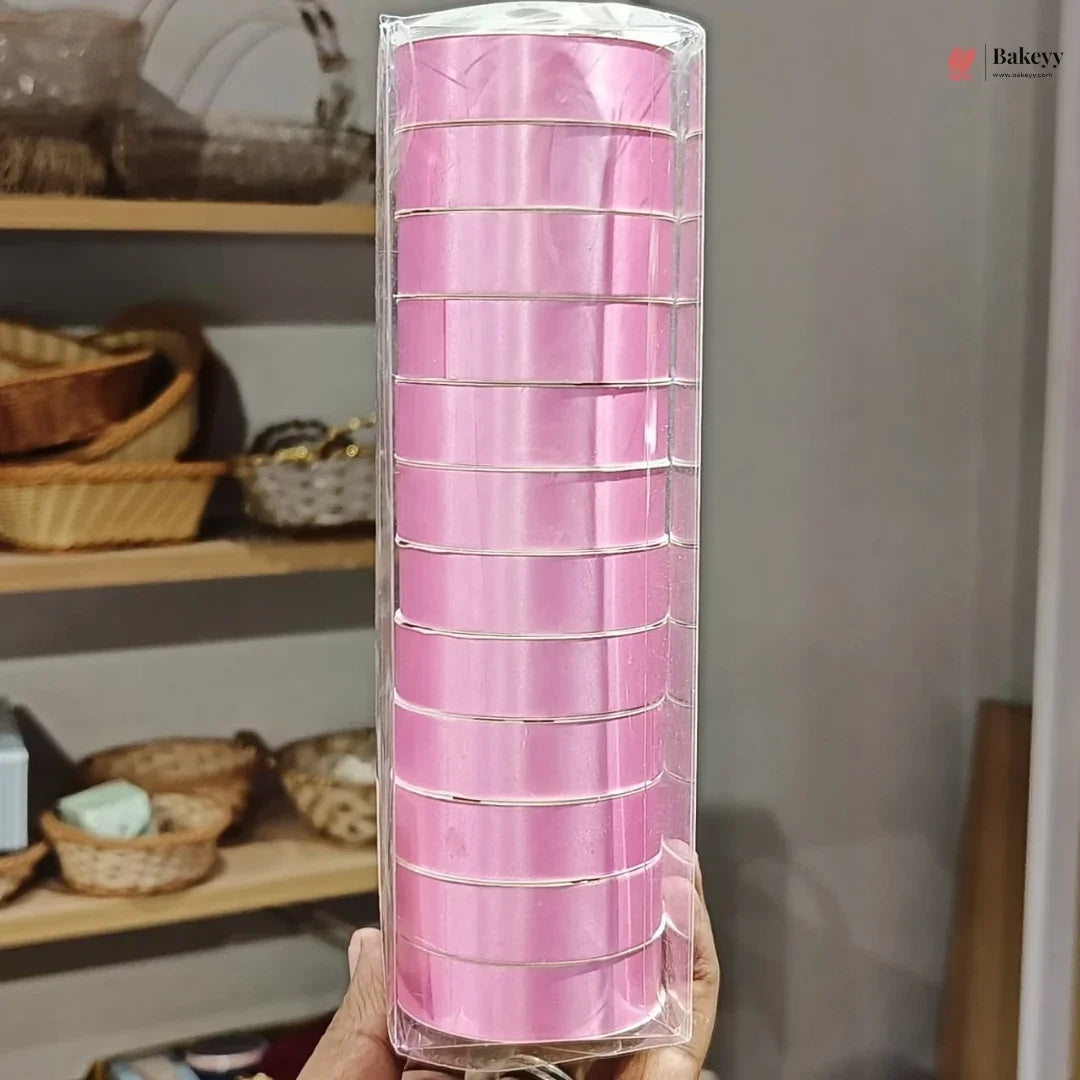 Roll of pink ribbon in clear packaging held in front of a shelf with wicker baskets.