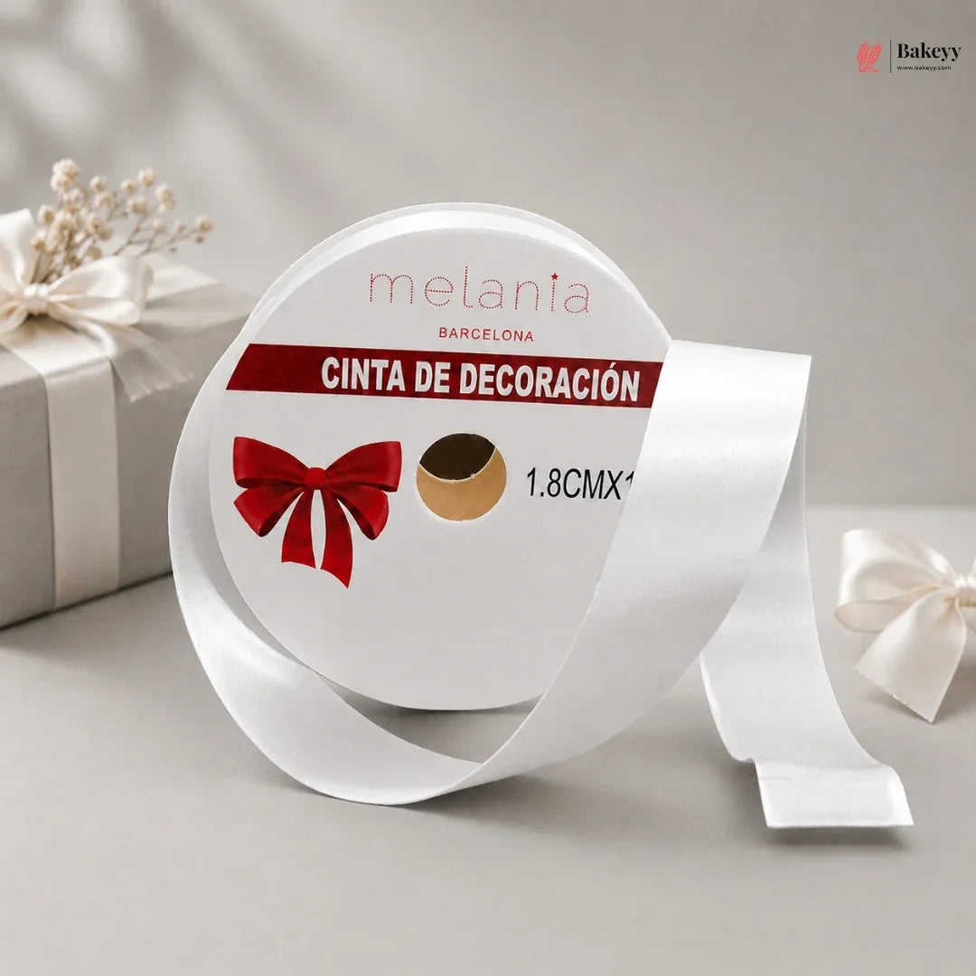 Roll of white decorative ribbon with a red bow design on a gray background