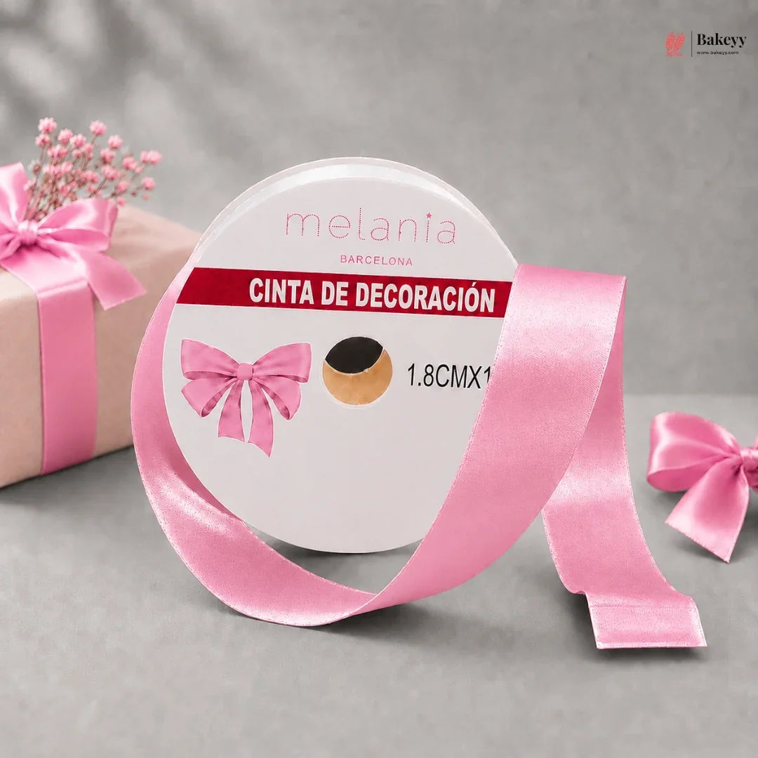 Roll of pink decorative ribbon with a bow on a gray background