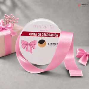 Roll of pink decorative ribbon with a bow on a gray background