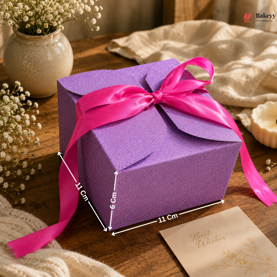Purple gift box with a pink ribbon on a wooden surface with decorative elements.