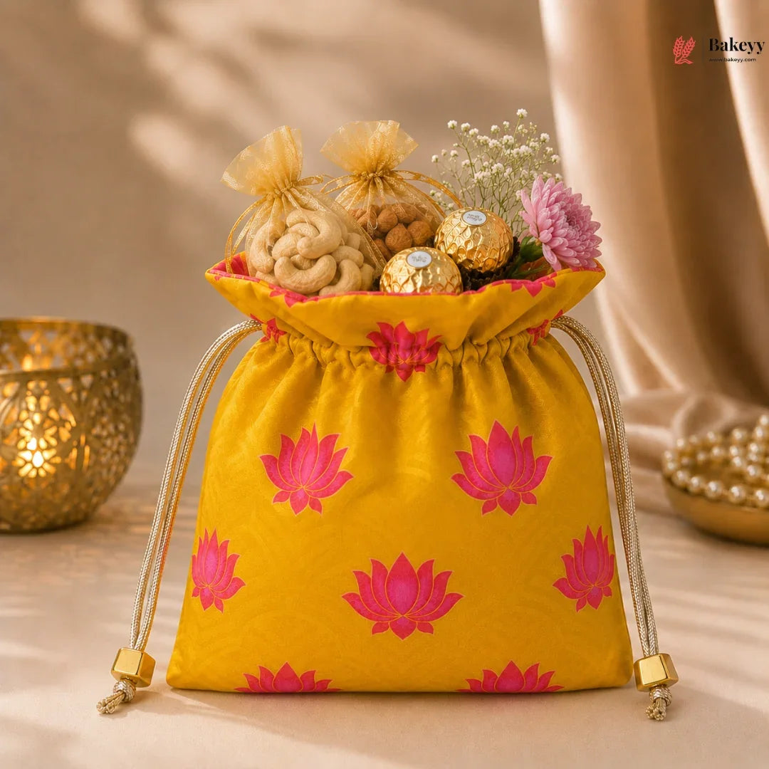 Yellow drawstring bag with pink lotus patterns filled with snacks and flowers, placed on a beige surface.