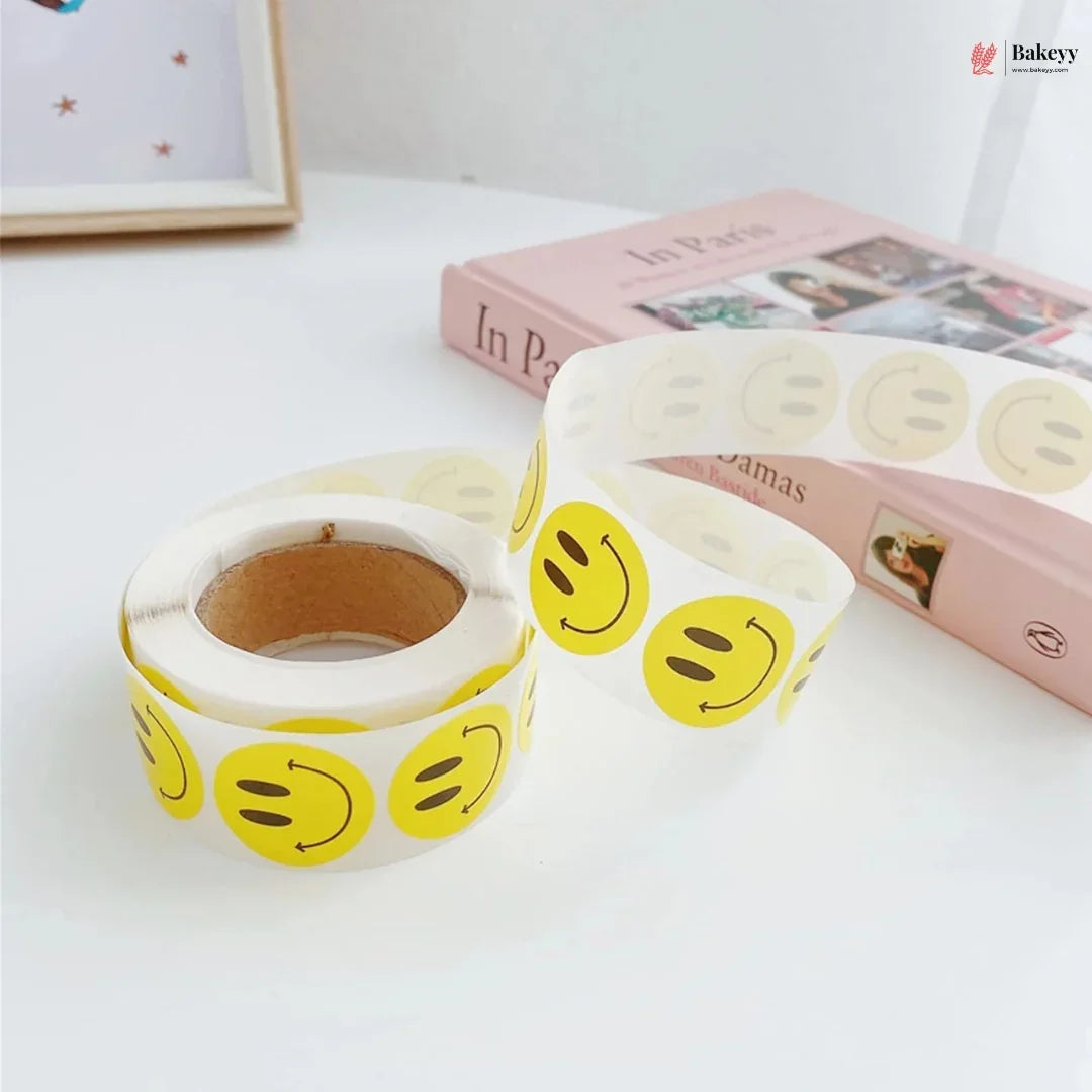 Rolls of yellow smiley face tape on a white surface with a pink book in the background.