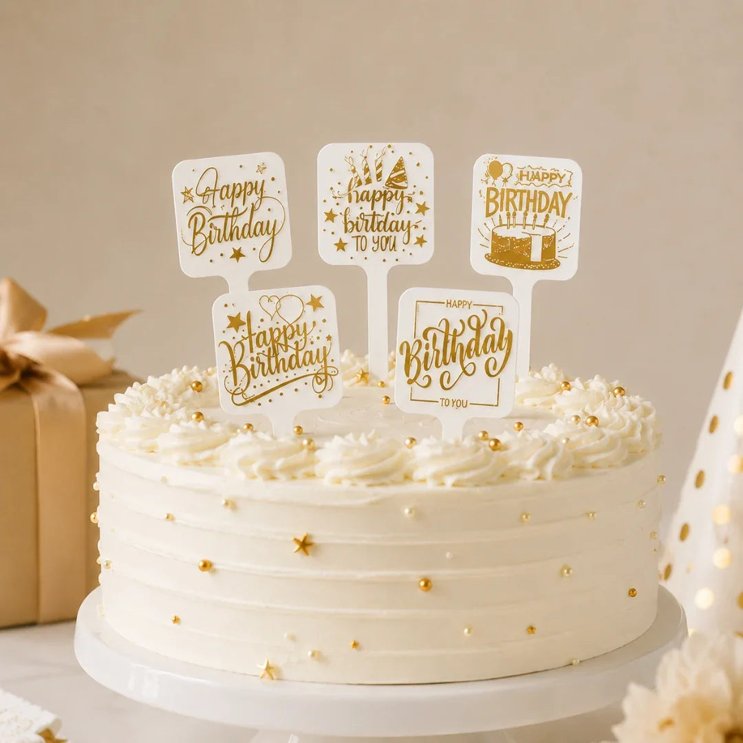White cake with gold decorations and 'Happy Birthday' topper on a neutral background