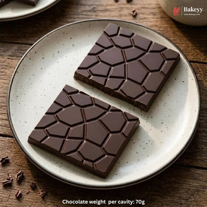 Two square dark chocolate bars with a raised geometric pattern, displayed on a speckled beige ceramic plate over a rustic wooden table. A Bakeyy watermark is visible in the top right corner, and text at the bottom reads 'Chocolate weight per cavity: 70g'.