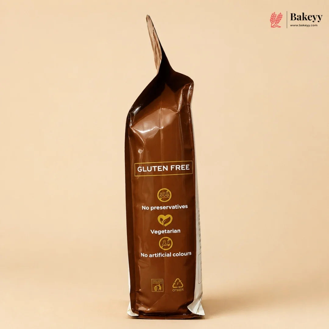 A stand-up pouch of Bakeey Gluten Free vegetarian flour, shown on a solid beige background. The packaging is dark brown with gold and white text detailing its gluten-free and vegetarian qualities.