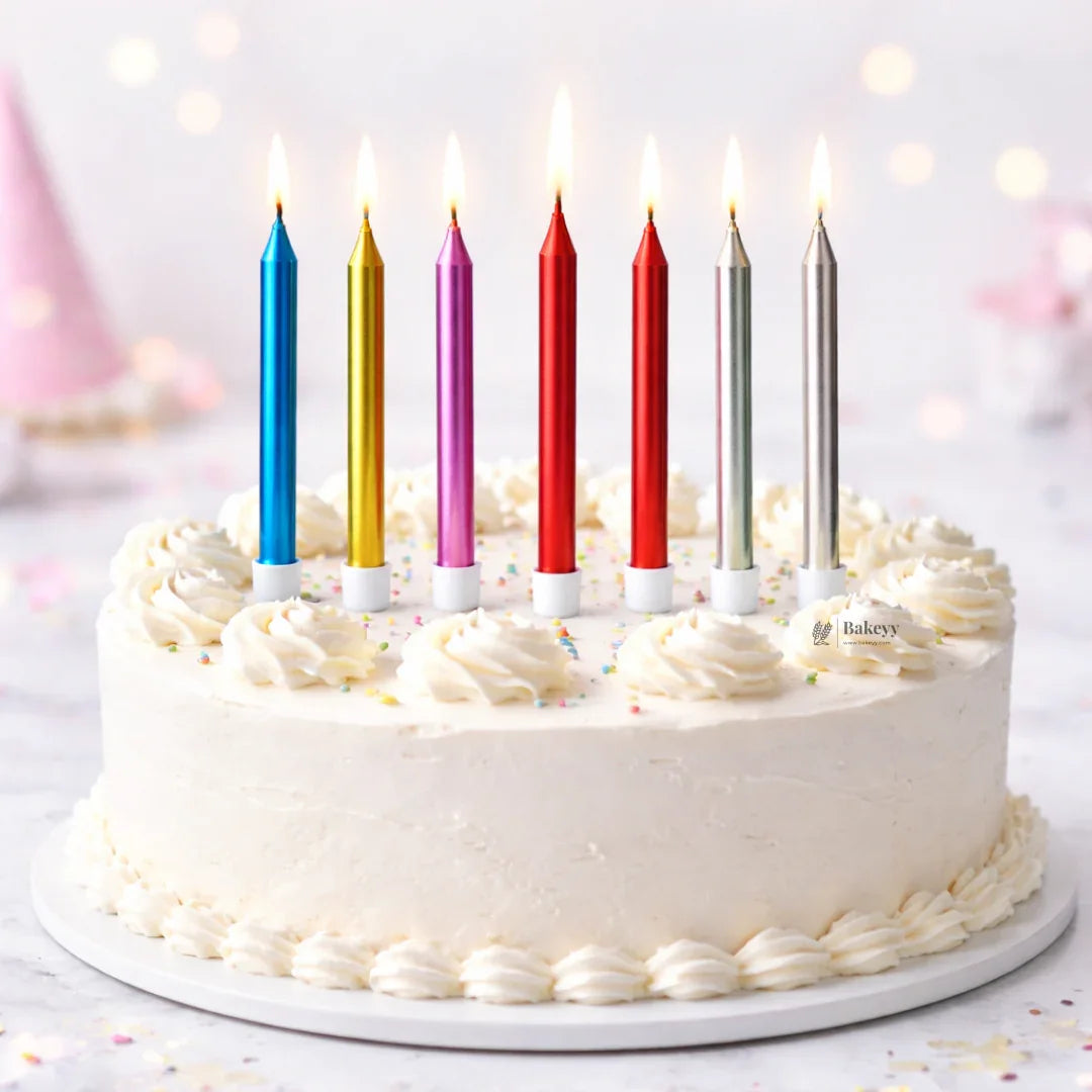 Bakeyy birthday cake with white frosting, colorful tall candles, and sprinkles