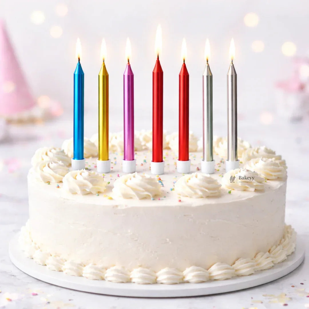 Bakeyy birthday cake with white frosting, colorful tall candles, and sprinkles