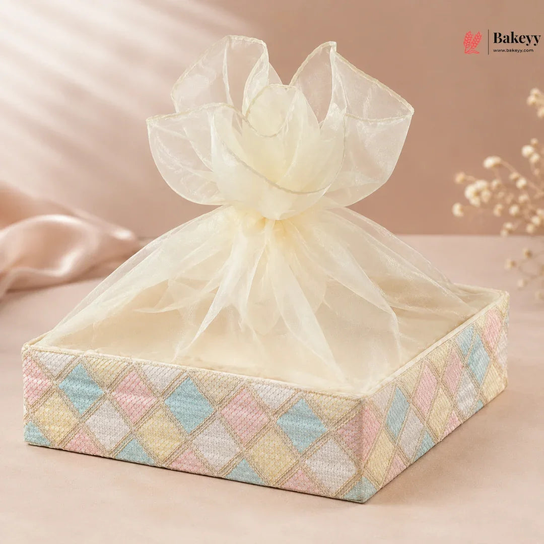 Decorative gift box with pastel diamond pattern and sheer ribbon on a soft pink background, featuring the brand 'Bakeyy'.