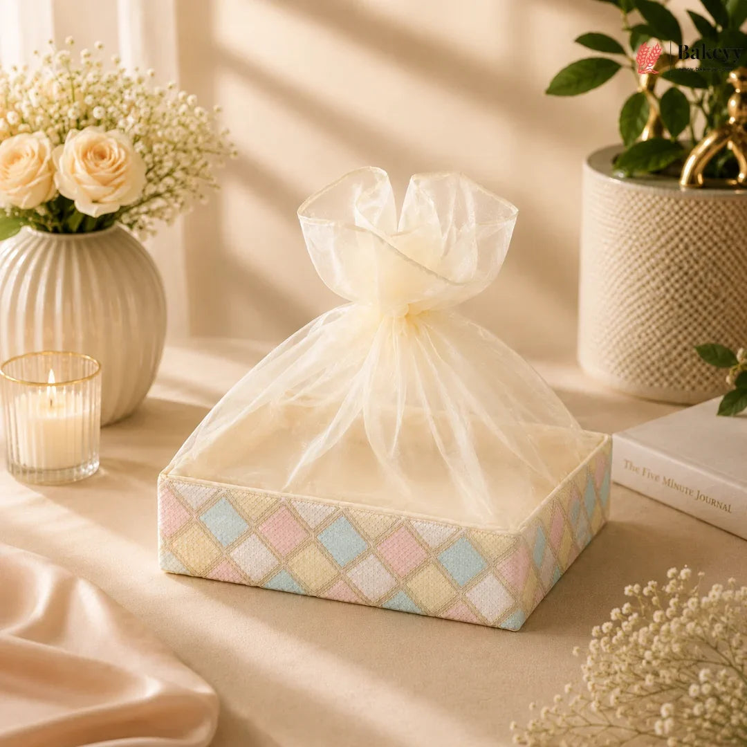 Decorative box with a sheer bow on a soft beige surface with flowers and candles.