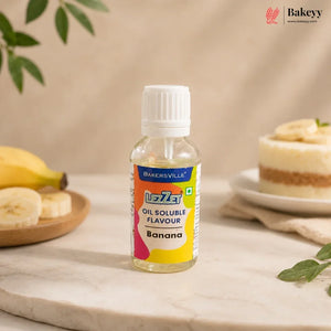A bottle of BakersVille L2Z3 Banana oil soluble flavouring syrup, set on a marble surface with banana slices and a banana cake in the background.
