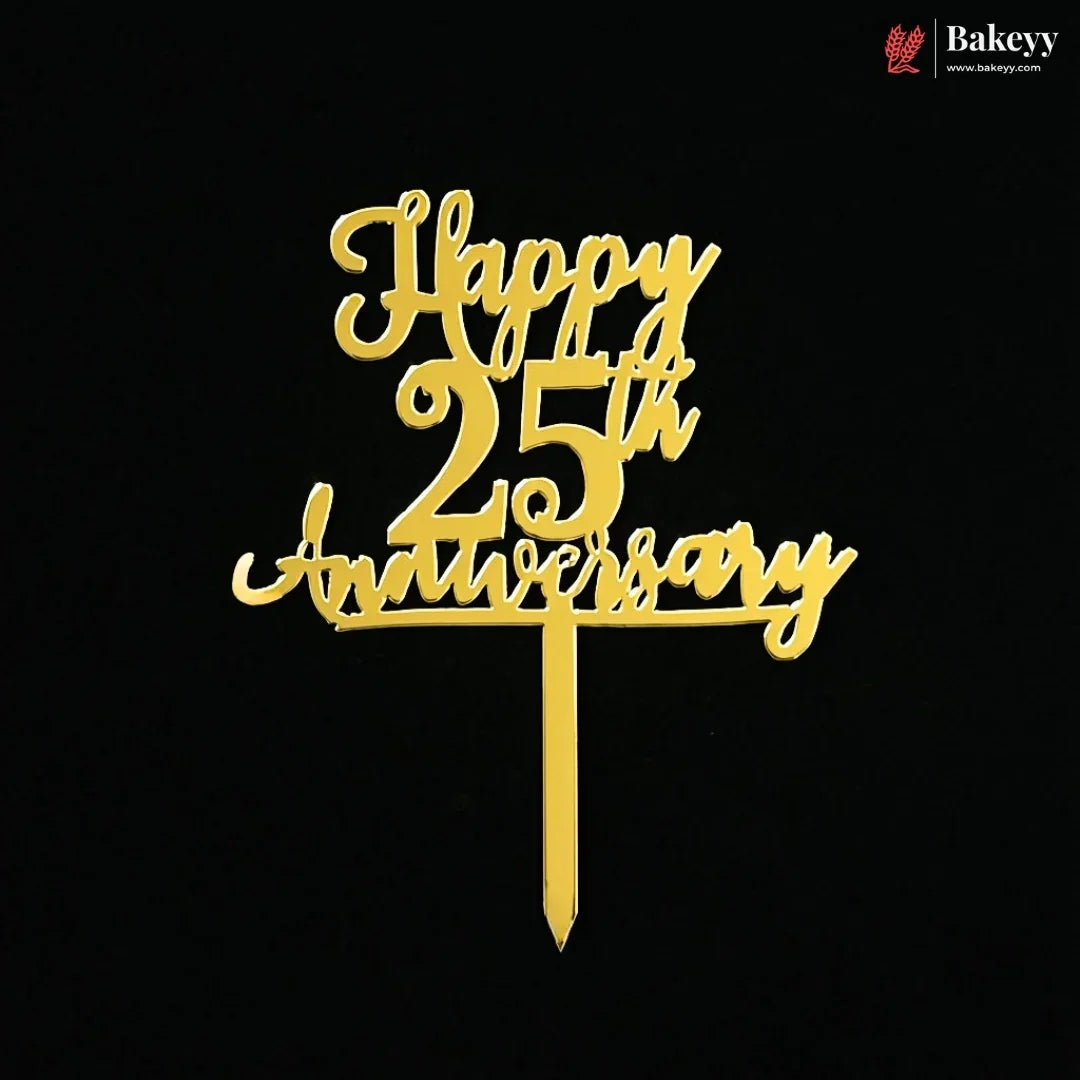 Gold metal cake topper with 'Happy 25th Anniversary' script on a black background, featuring a Bakeyy logo in the top right corner.