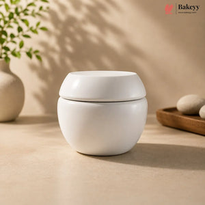 White ceramic container with lid on a beige surface, with 'Bakeyy' branding in the corner.