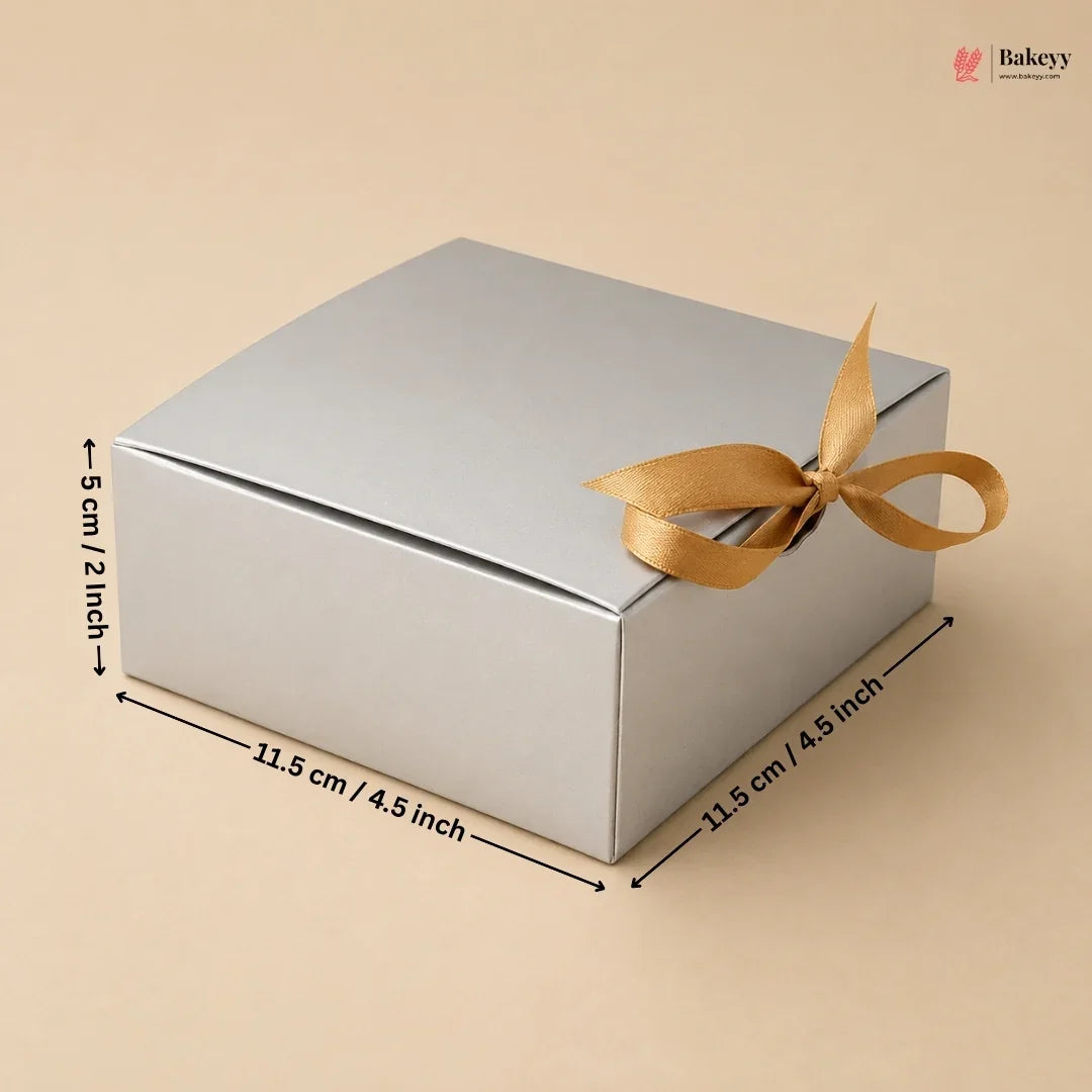 Silver gift box with a gold ribbon and dimensions on a beige background