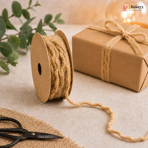 Spool of jute twine, scissors, and a wrapped gift with a bow on a neutral background.