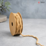 Spool of natural jute twine on a gray surface with a blurred background