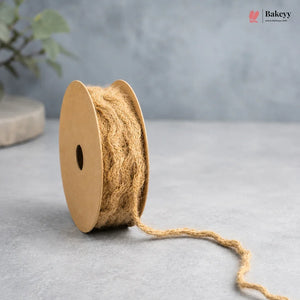 Spool of natural jute twine on a gray surface with a blurred background