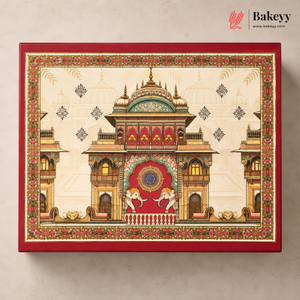 A rectangular red gift box with an ornate traditional palace illustration on the lid, photographed against a light beige wall. The Bakeyy logo appears in the top right corner.