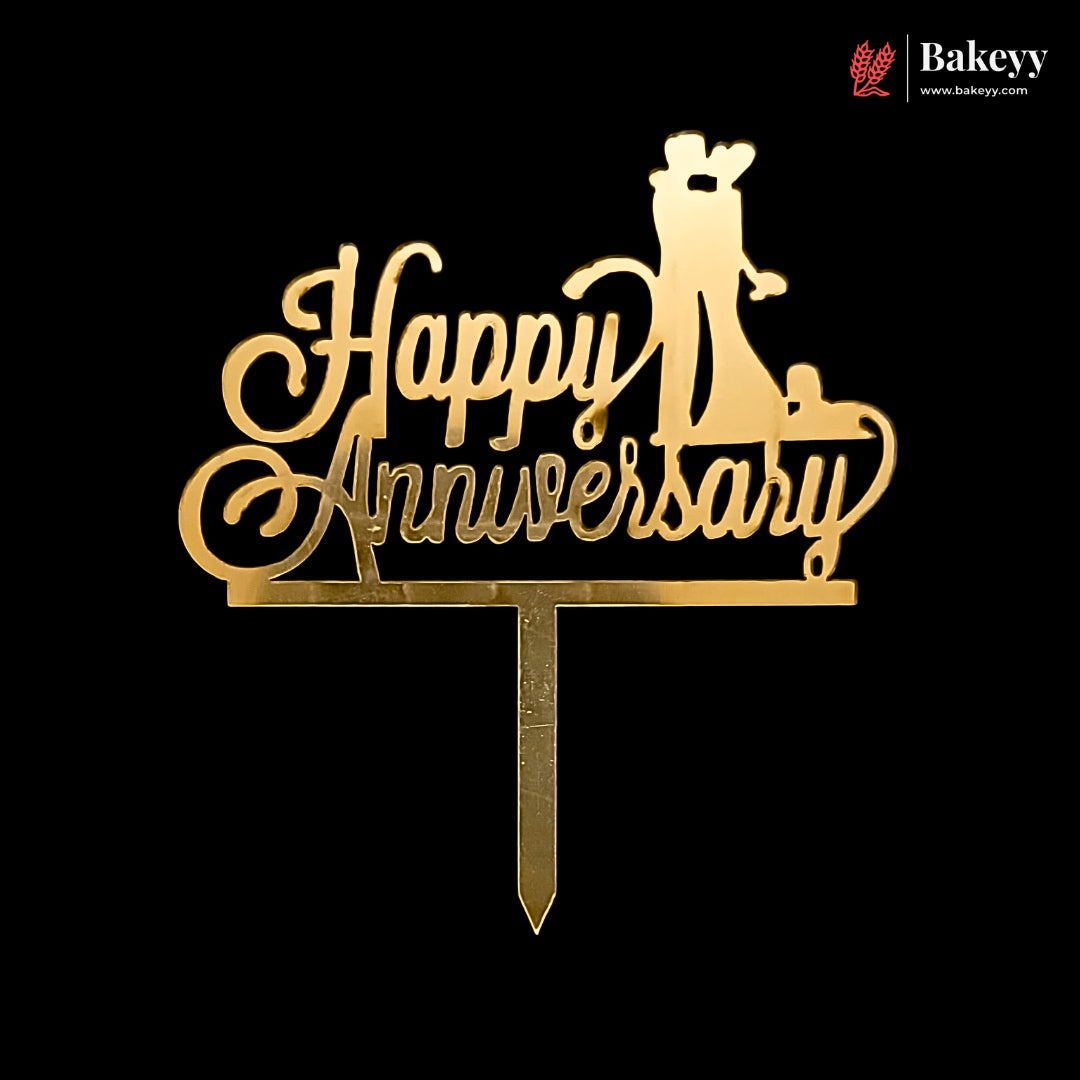 Gold acrylic 'Happy Anniversary' cake topper with a silhouette of a bride and groom on a black background, featuring a Bakeyy brand watermark in the top right corner.