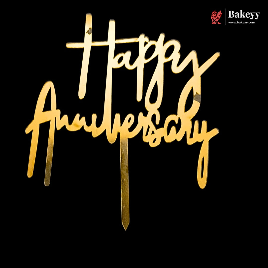 Gold wooden 'Happy Anniversary' cake topper with a single stake, shown against a solid black background. A Bakeey brand watermark is visible in the top right corner.
