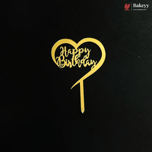 A gold heart-shaped cake topper with 'Happy Birthday' written in cursive script, displayed on a black background with a Bakeyy logo in the top right corner.