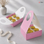 Pink packaging box with gold lids on a gray surface, featuring the Bakeyy brand.