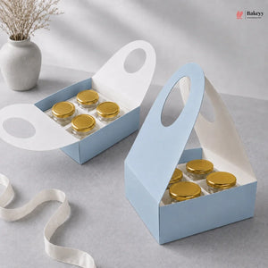 Two blue gift boxes with gold lids containing small jars on a gray surface.