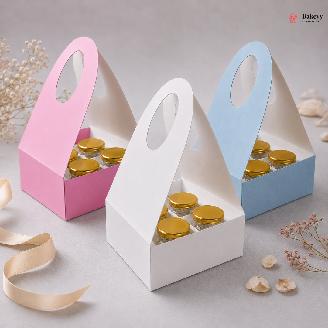 Three small cardboard boxes with gold lids, one pink, one white, and one blue, on a light gray background.