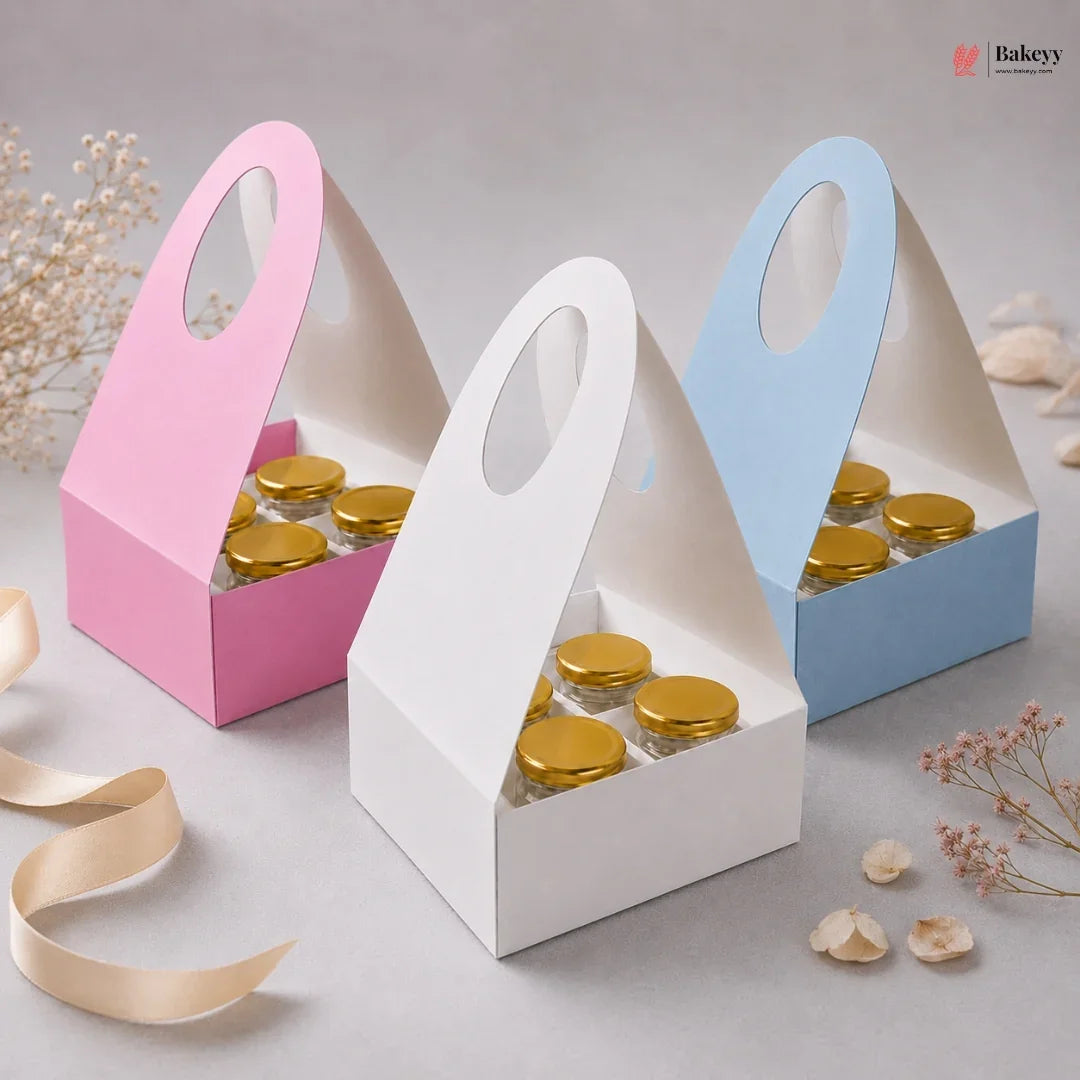 Three small cardboard boxes with gold lids, one pink, one white, and one blue, on a light gray background.