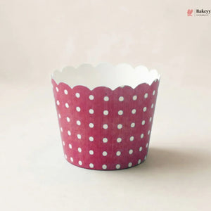 A single scalloped cupcake liner with a pink and white polka dot pattern, photographed on a light beige background.