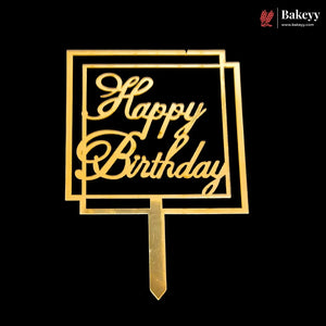 Gold metal Happy Birthday cake topper with a geometric frame design and stake, shown on a solid black background.