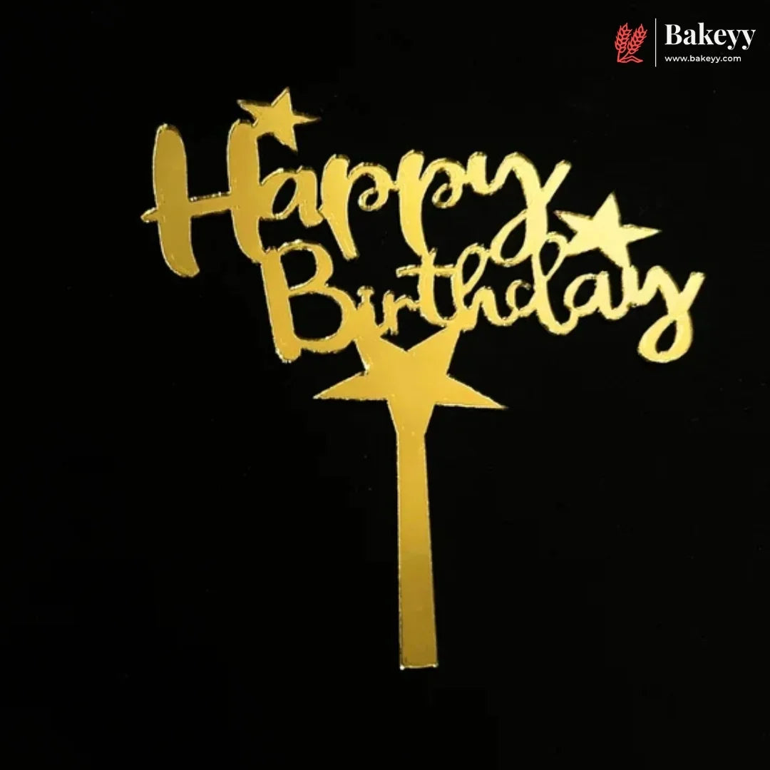 Gold foil 'Happy Birthday' cake topper with star accents and a wand-shaped base, shown on a black background. A Bakeey logo watermark is visible in the top right corner.
