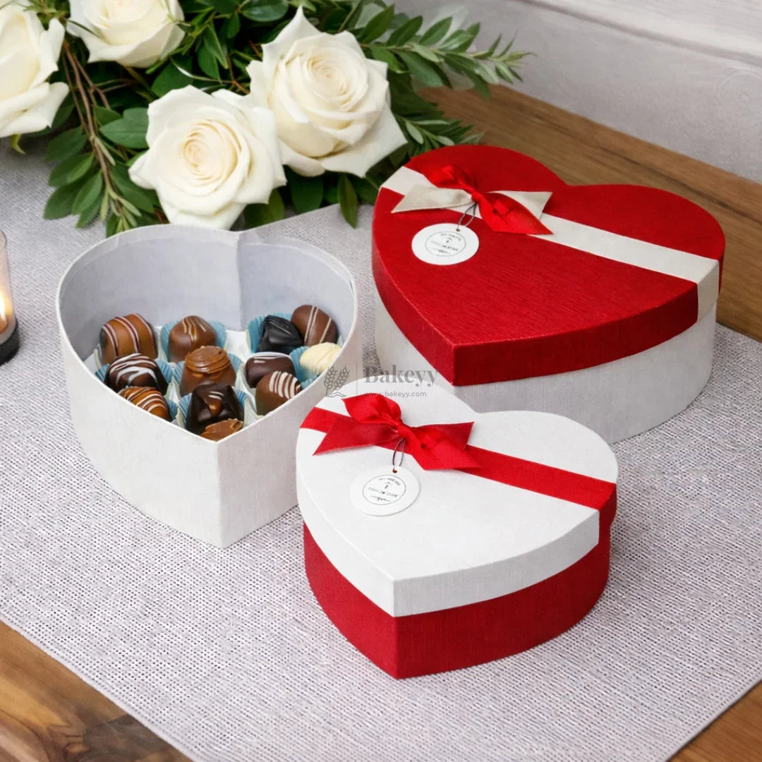 Heart-shaped gift boxes with chocolates, red ribbon, roses, and elegant packaging by Bakeyy.