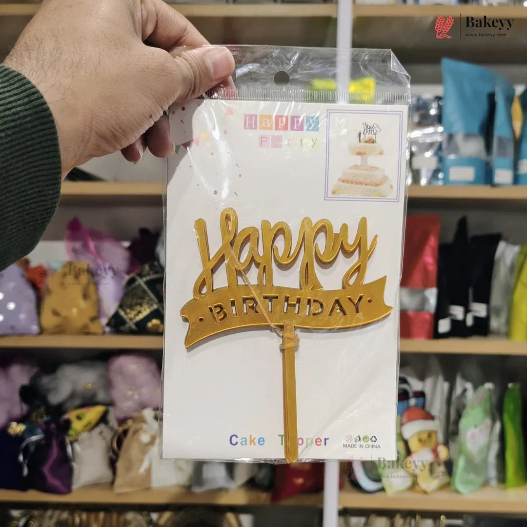 Hand holding a 'Happy Birthday' cake topper packaging in a store setting