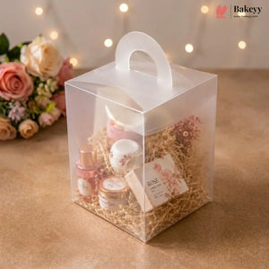 Clear gift box with cosmetic products and flowers on a wooden surface with blurred lights in the background