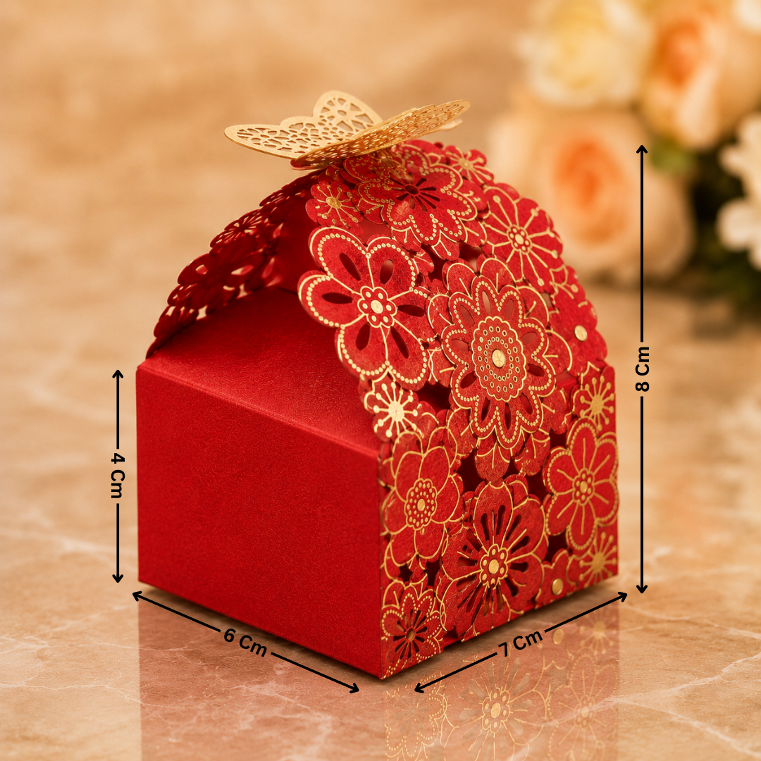 Decorative red gift box with floral designs and gold accents, placed on a reflective surface with a blurred floral background.