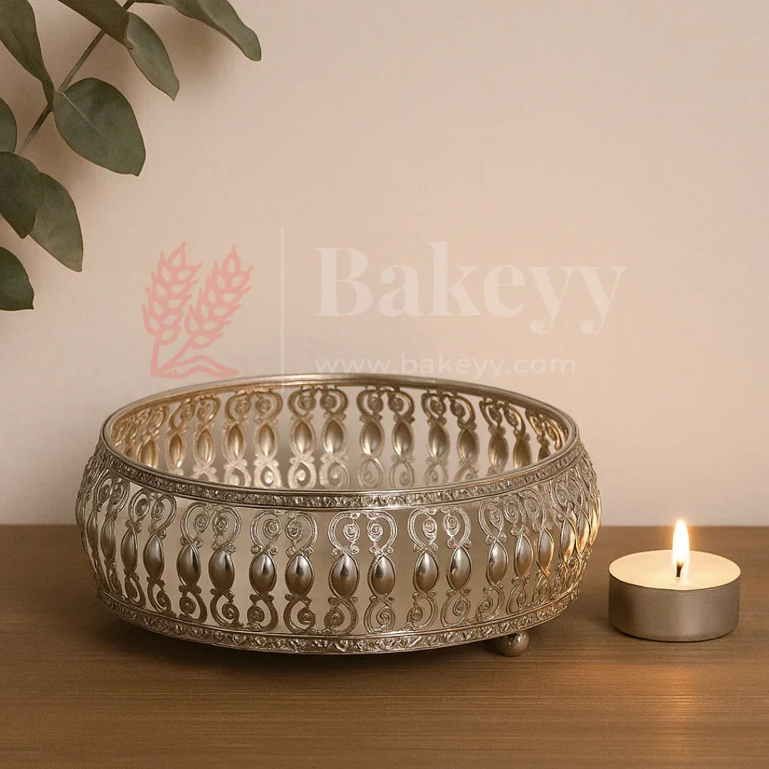 Decorative metal bowl with intricate patterns on a wooden surface next to a lit candle, with 'Bakeyy' branding.