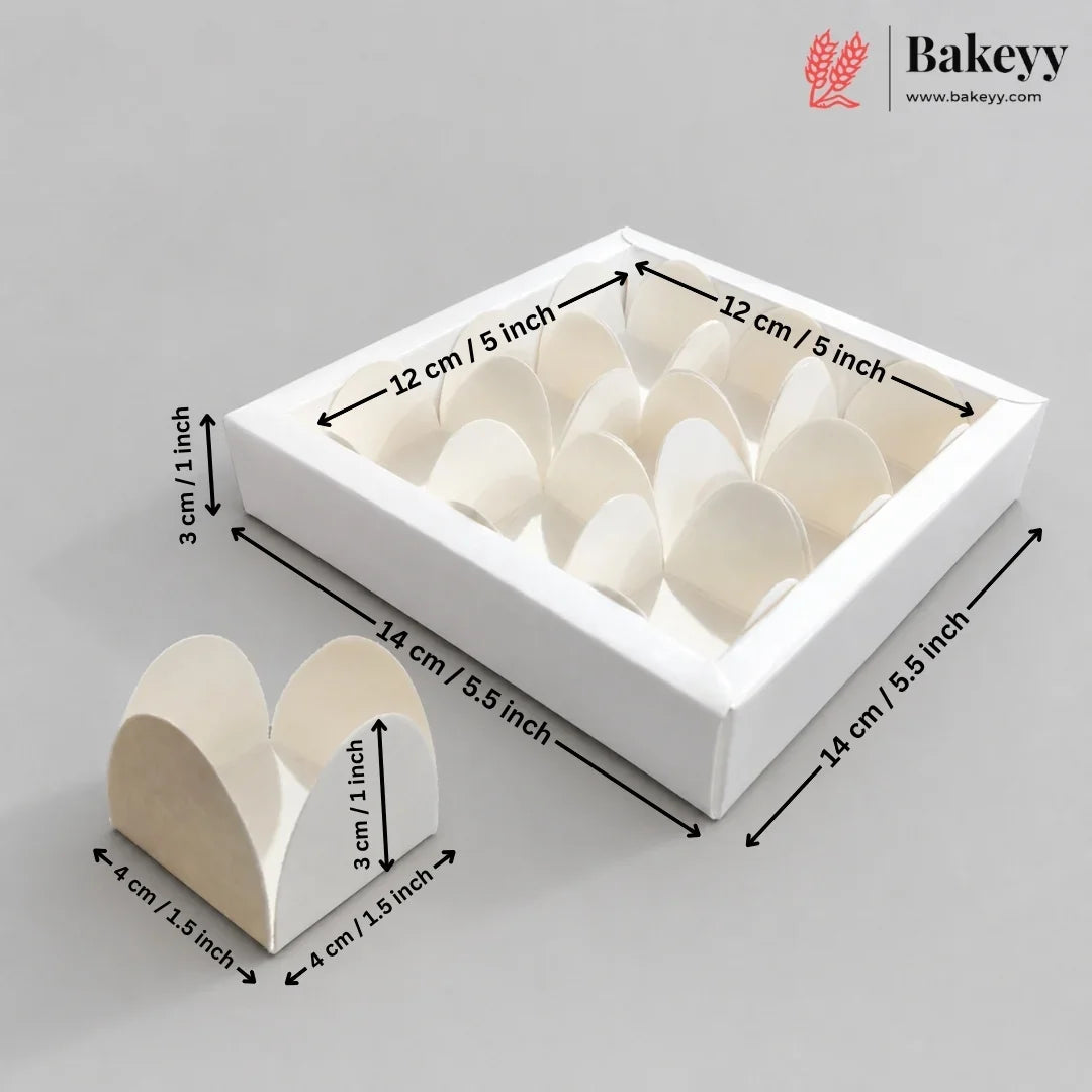 White square bakery box with multiple heart-shaped paper insert compartments, shown with dimension arrows and labels indicating 14 cm by 12 cm by 3 cm measurements on a light gray background. A smaller standalone heart-shaped insert is shown in front, and the Bakeyy logo appears in the top right.