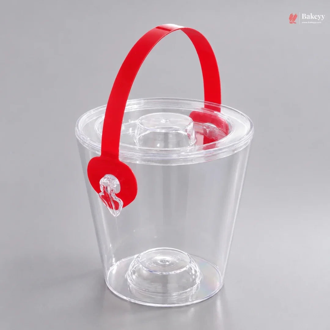 Clear plastic ice bucket with a red handle on a gray background
