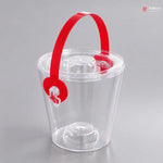 Clear plastic ice bucket with a red handle on a gray background