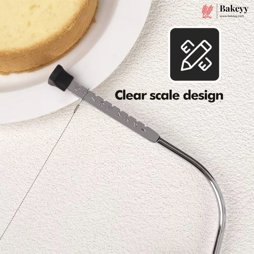 A metal cake level scale tool with a clear window and black end cap, shown on a white textured surface next to a partially visible cake slice. Text reads 'Clear scale design' and the Bakeyy brand logo appears in the top right.