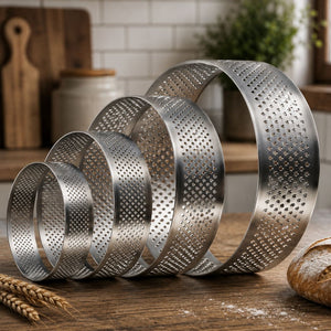 Set of metal ring molds on a wooden surface with bread and wheat in the background