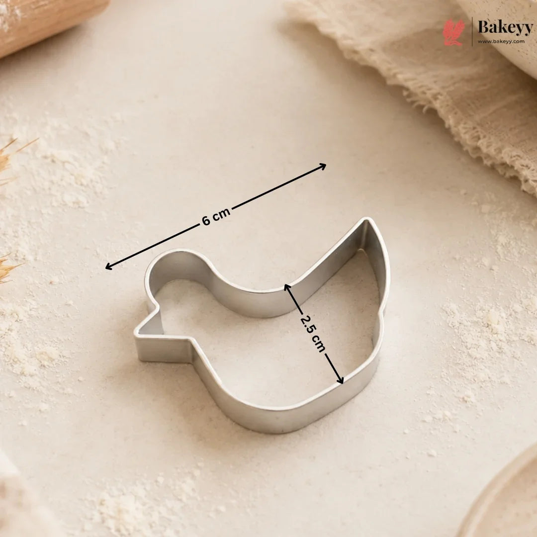 Metallic bird-shaped cookie cutter with measurements on a light surface, branded 'Bakey'.