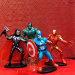 Four superhero action figures on a red surface with a red patterned background