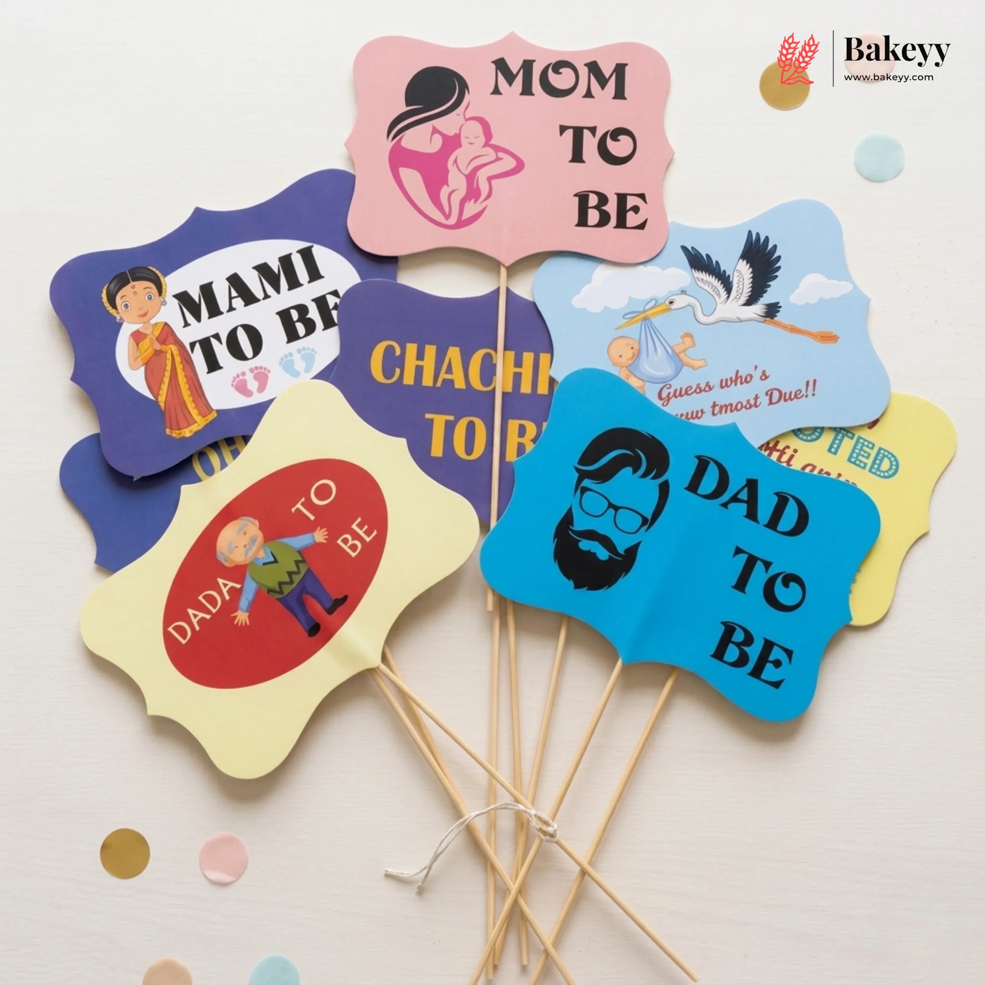 Colorful baby shower props with text like 'Mom to be', 'Dad to be', and 'Chacha to be' on sticks.
