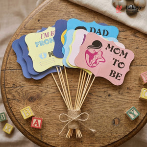 Set of baby shower-themed paper fans on a wooden surface with colorful letters around.