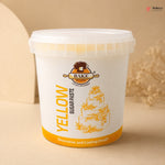 White container of yellow sugar paste with a cake illustration on a beige background
