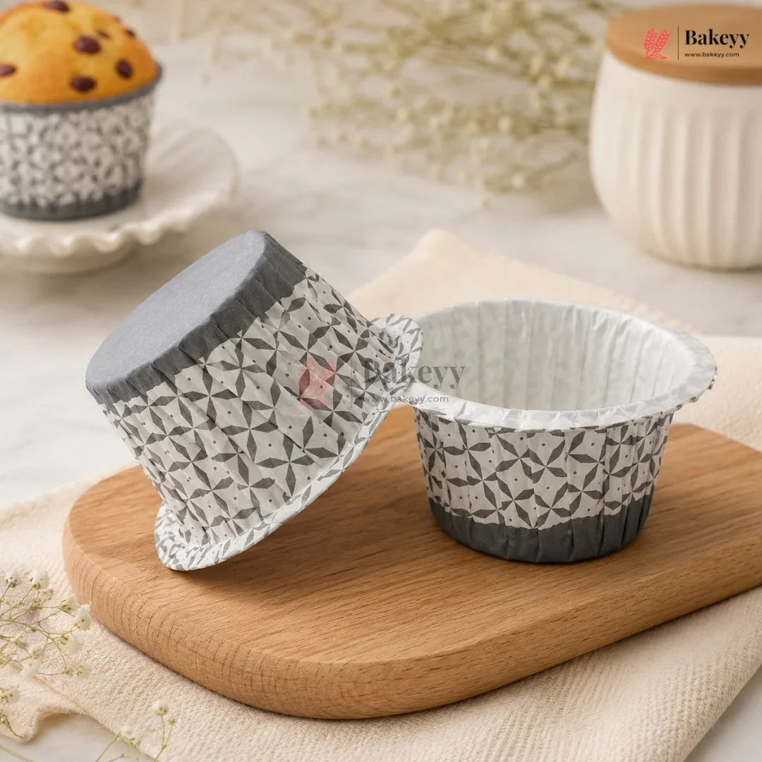 Patterned paper cupcake liners on a wooden board with a muffin in the background.