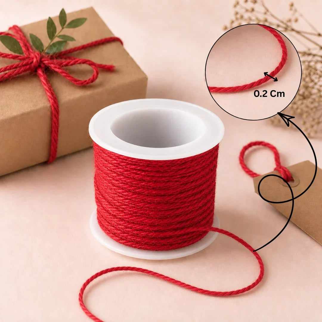 Spool of red string with a gift box tied with red string on a beige background
